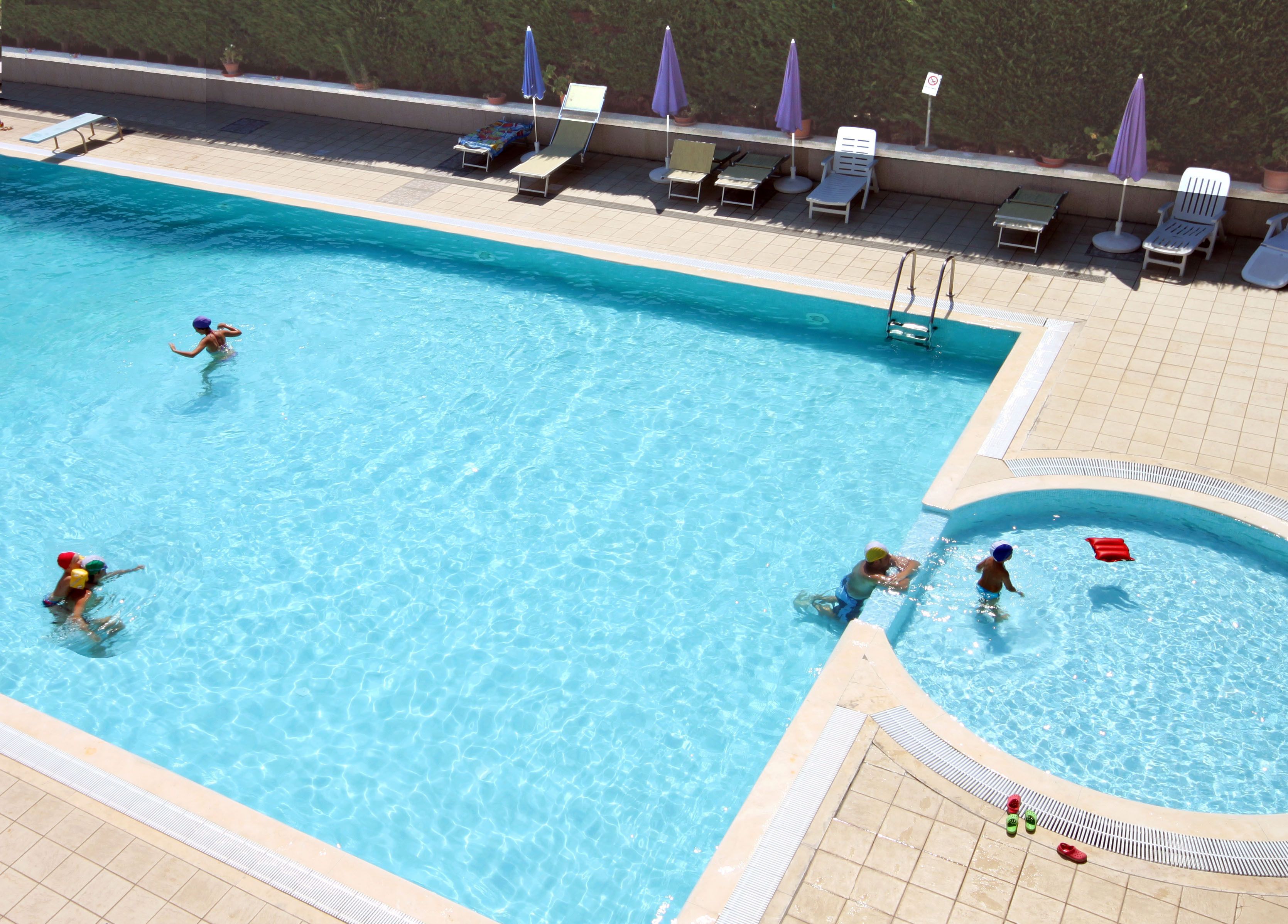 A swimming pool with multiple lanes, sun loungers, and umbrellas.