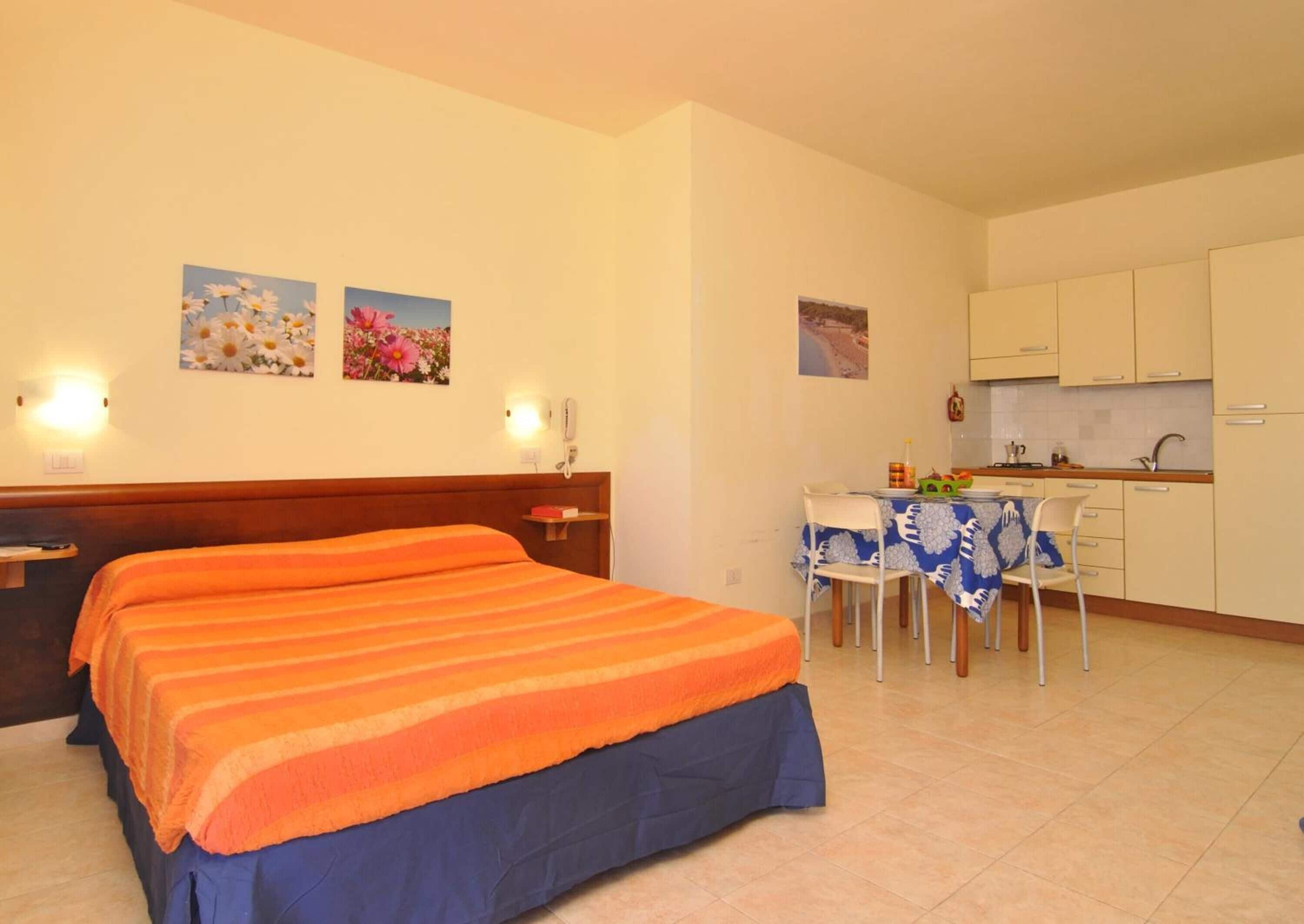A hotel room with two beds, a small kitchenette, and a dining area.