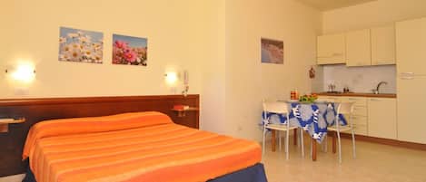 Habitación de hotel con dos camas, un pequeño kitchenette y una zona de comedor.