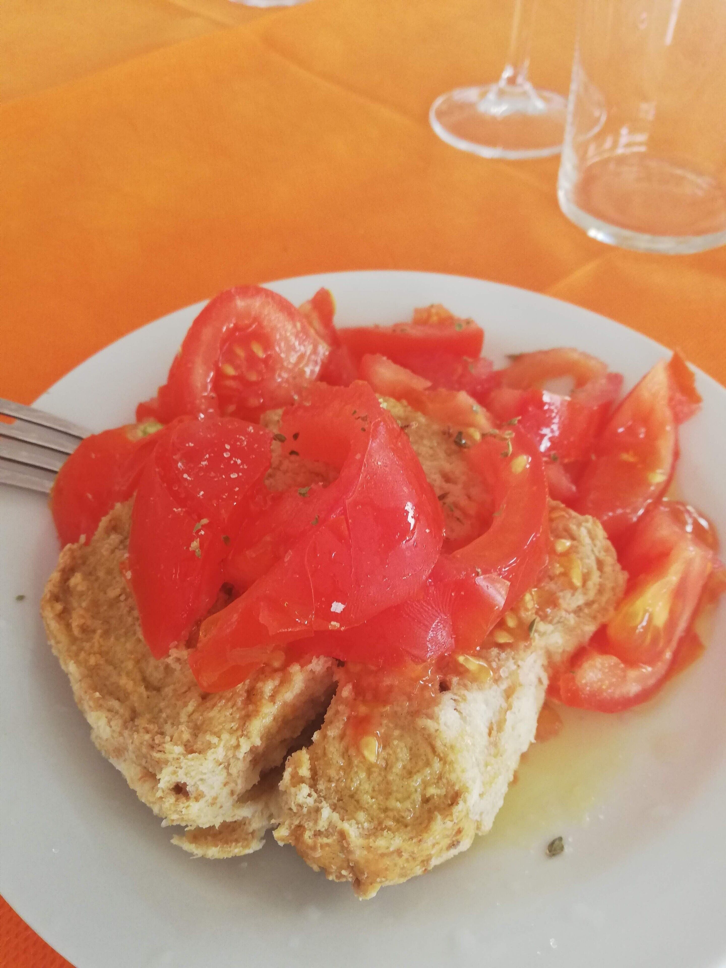 Une assiette de bruschettas garnies de tranches de tomates et d’huile d’olive.