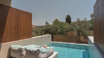 A modern outdoor pool area with two cushioned seating areas and a clear view of the surrounding landscape.