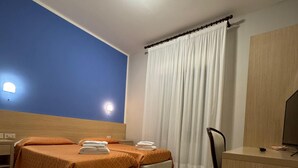 A hotel room with two beds, a desk, a chair, a TV, and a bathroom. - Albergo La Posta Arezzo (Civitella in Val di Chiana)