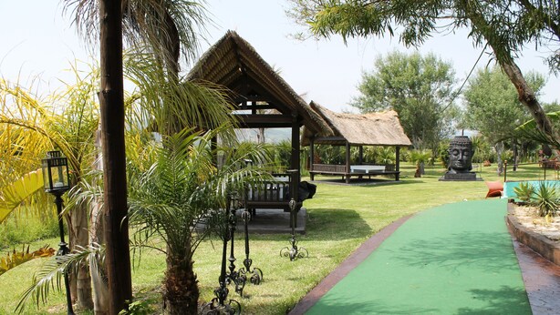 A gazebo with a thatched roof, surrounded by greenery and a paved path. - Copacabana Beach Tarifa (Tarifa)