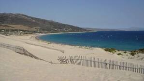 A coastal landscape with a sandy beach, a wooden fence, and a clear blue sea. - Copacabana Beach Tarifa (Tarifa)