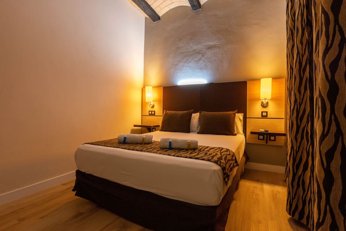 Ein Hotelzimmer mit einem großen Bett, zwei Nachttischen und einem Kopfteil mit integrierter Beleuchtung.