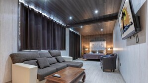 A modern hotel room with a large sectional sofa, a wooden coffee table, and a bed with a headboard. - Copacabana Beach Tarifa (Tarifa)