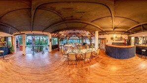 A spacious indoor area with a curved ceiling, a central dining table surrounded by chairs, and a bar area with stools. - Copacabana Beach Tarifa (Tarifa)