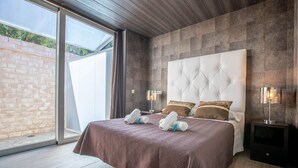 A modern bedroom with a large bed, a glass door leading to a balcony, and a nightstand with a lamp. - Copacabana Beach Tarifa (Tarifa)