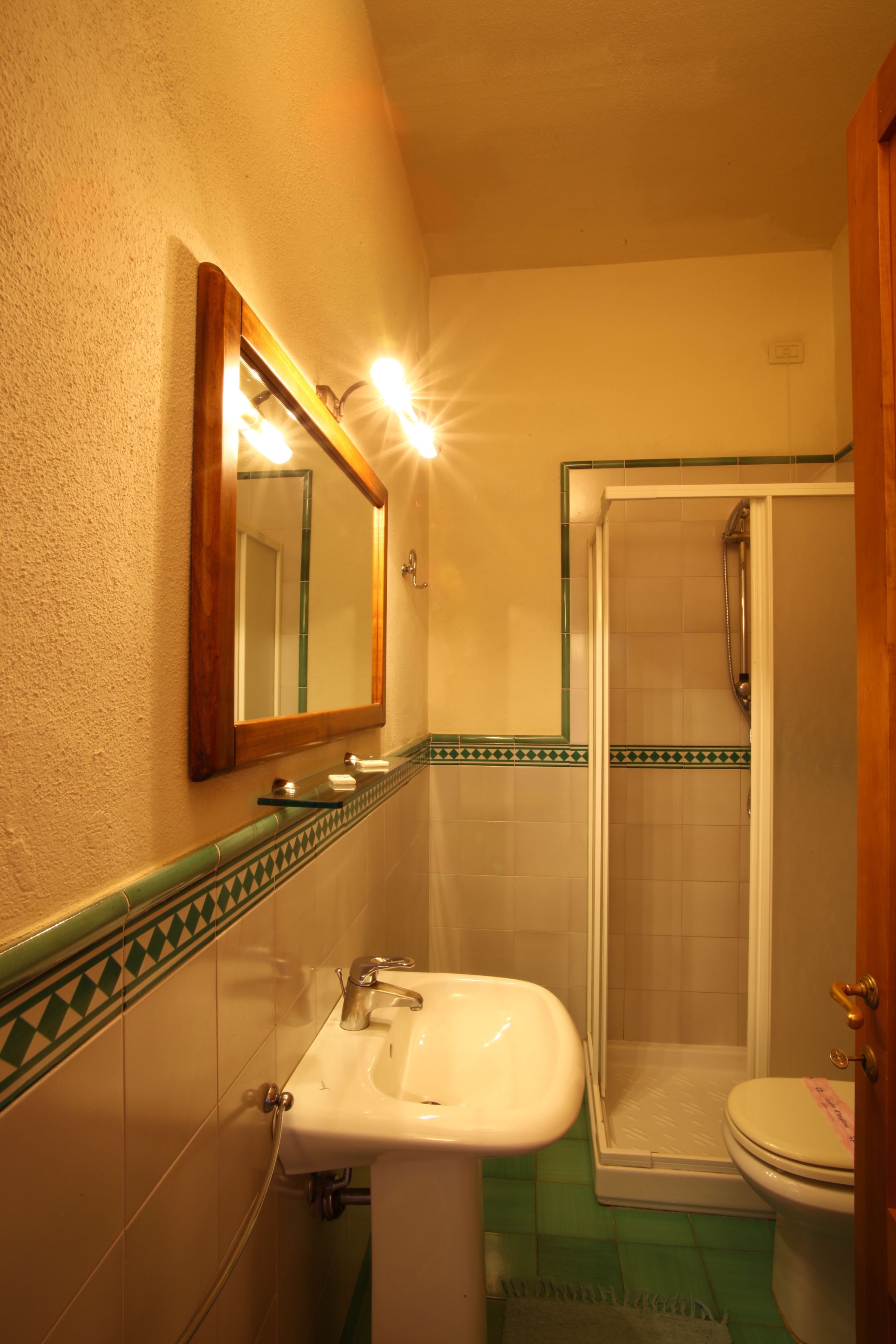 A bathroom with a white sink, a mirror, and a shower enclosure.
