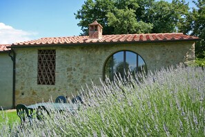 A stone building with a tiled roof, a chimney, and a circular window. - Podere il Pino (Poggibonsi)