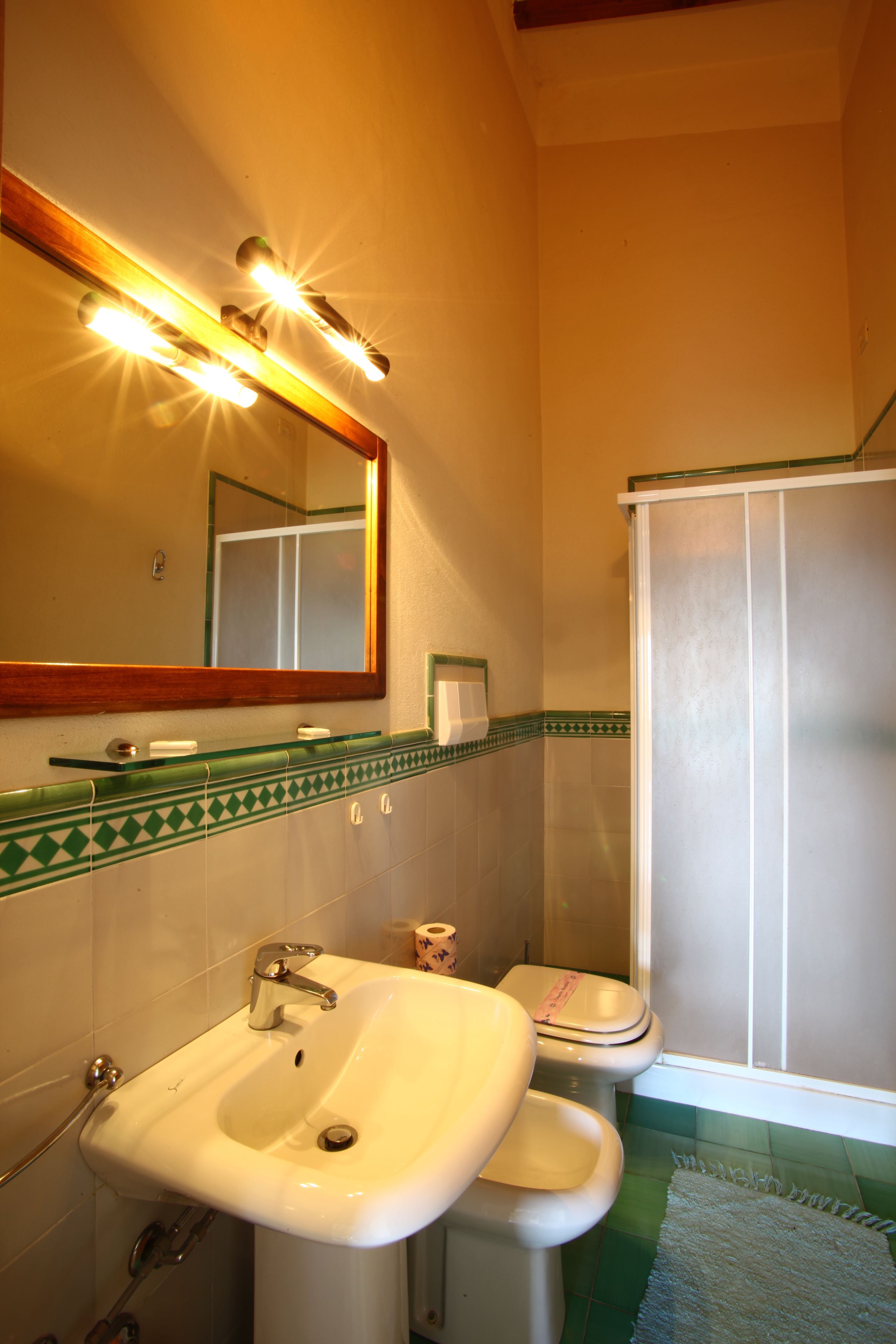 A bathroom with a sink, mirror, and shower.