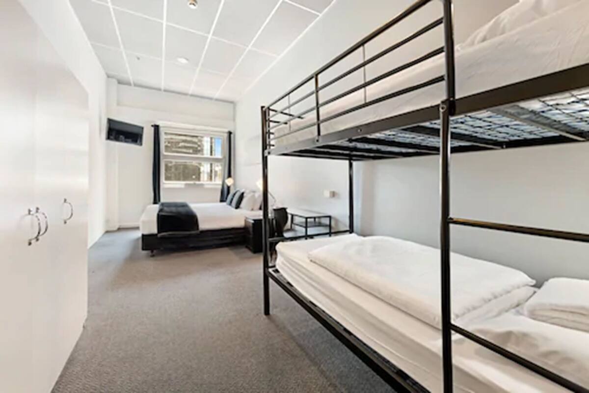 A bunk bed room with a desk and chair, a window, and a door.