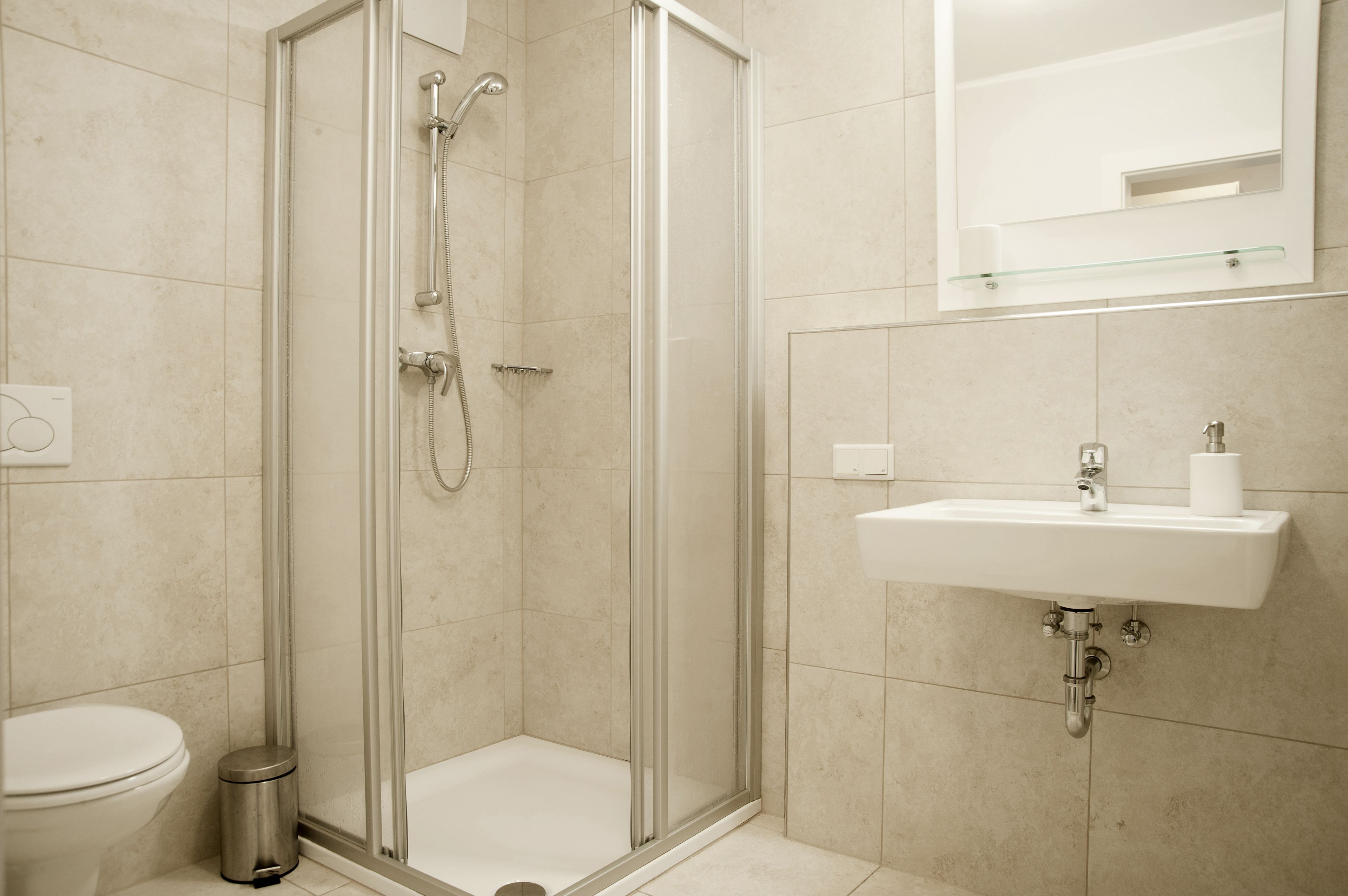 A modern bathroom with a glass-enclosed shower, a white sink, and a toilet.