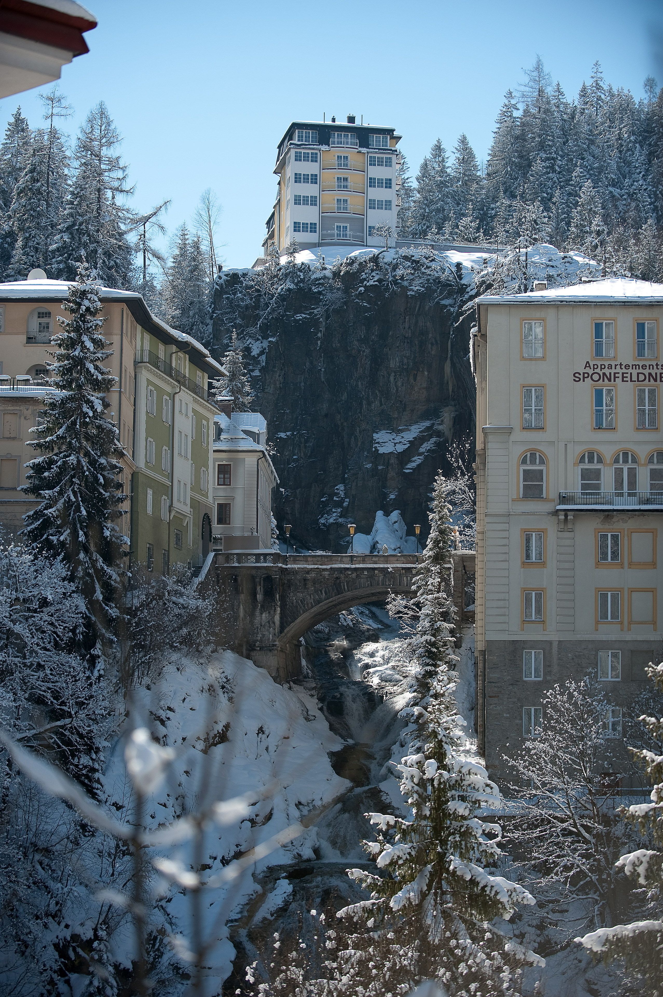 A building with multiple floors, a bridge, and snow-covered trees.