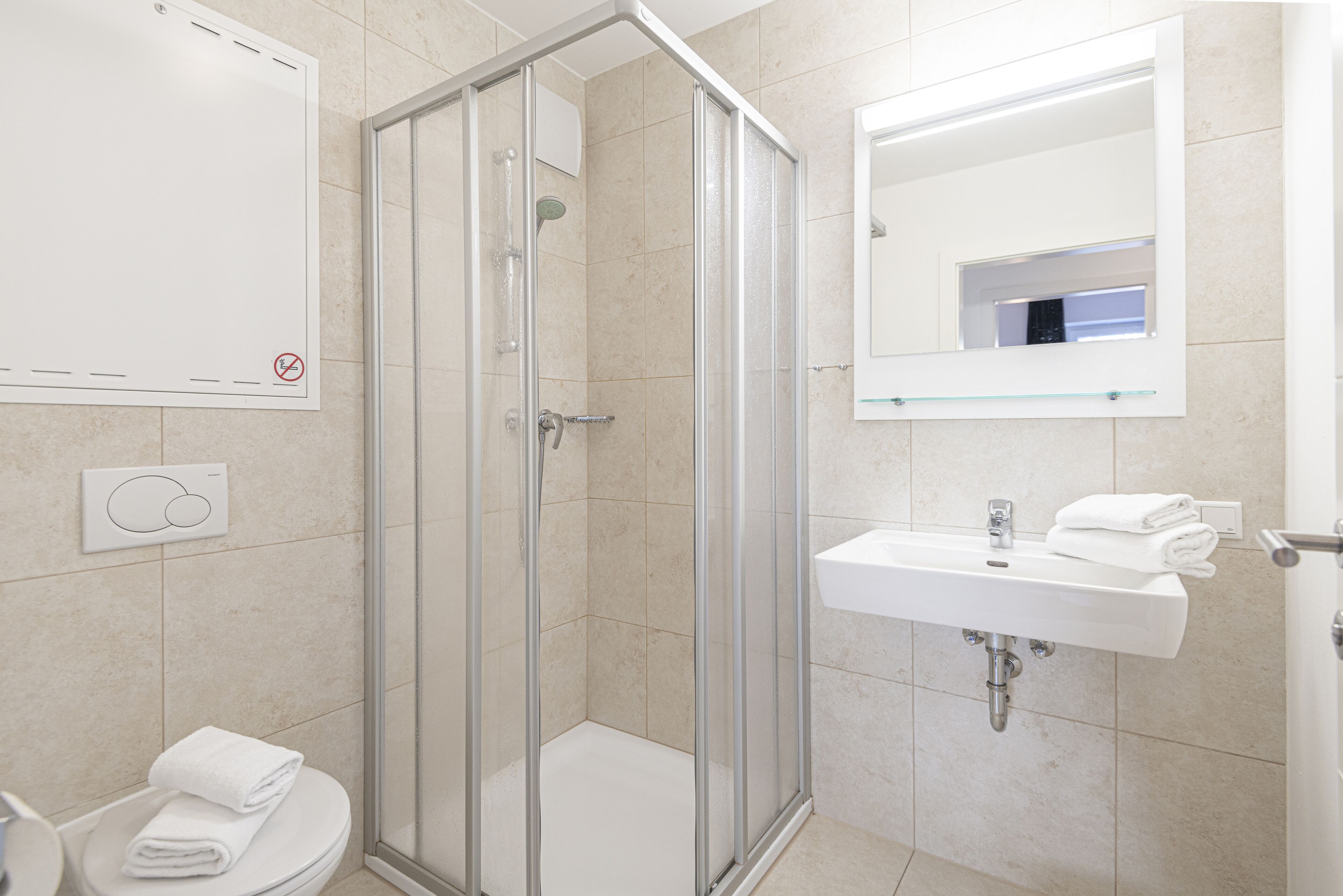 Une salle de bain moderne avec une douche à parois de verre, un lavabo blanc et des toilettes.