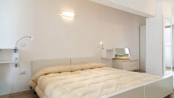 Ein Schlafzimmer mit Bett, Nachttisch, Spiegel und Wandleuchte.