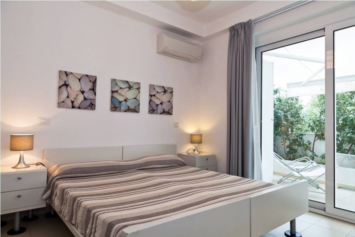 A bedroom with a bed, bedside tables, and wall art.