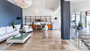 Un amplio salón con un sofá moderno, una mesa de centro de vidrio y una estantería.