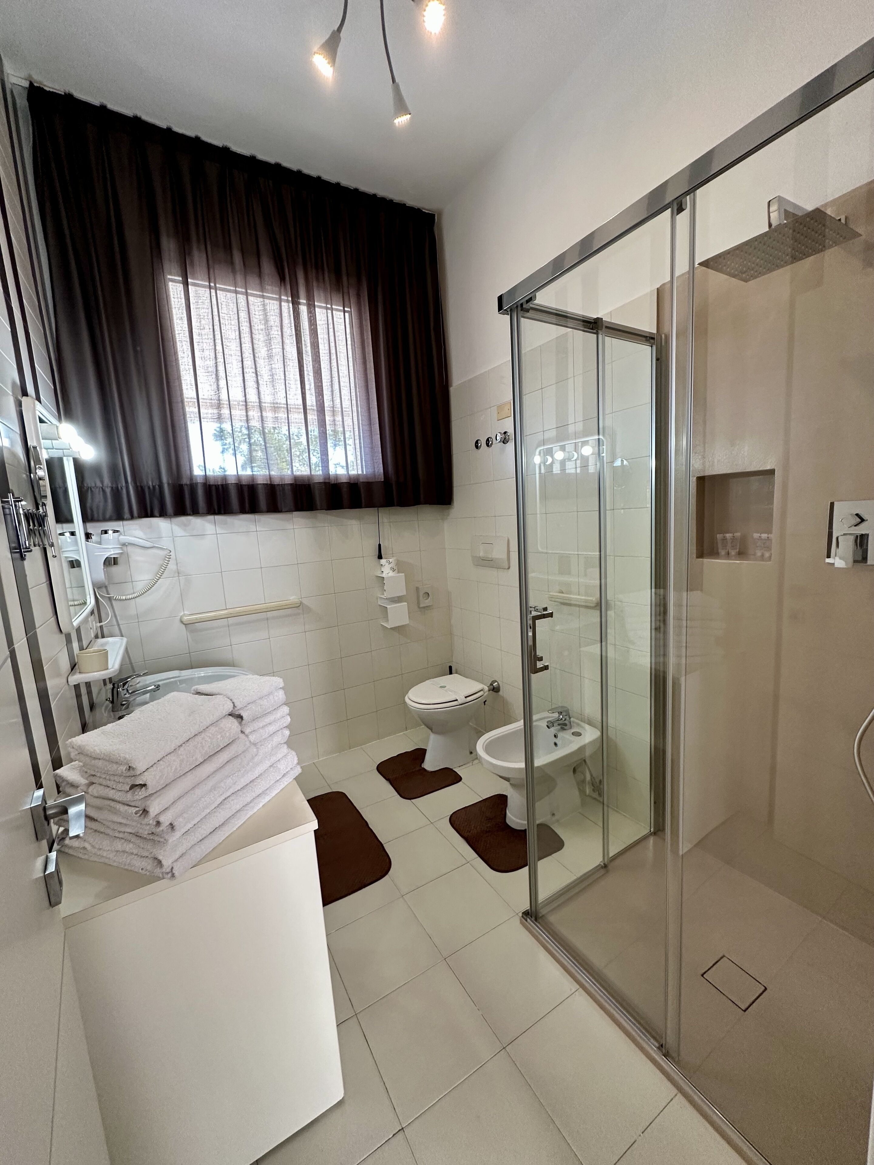 Ein modernes Badezimmer mit Duschkabine aus Glas, Toilette, Bidet und Waschbecken.