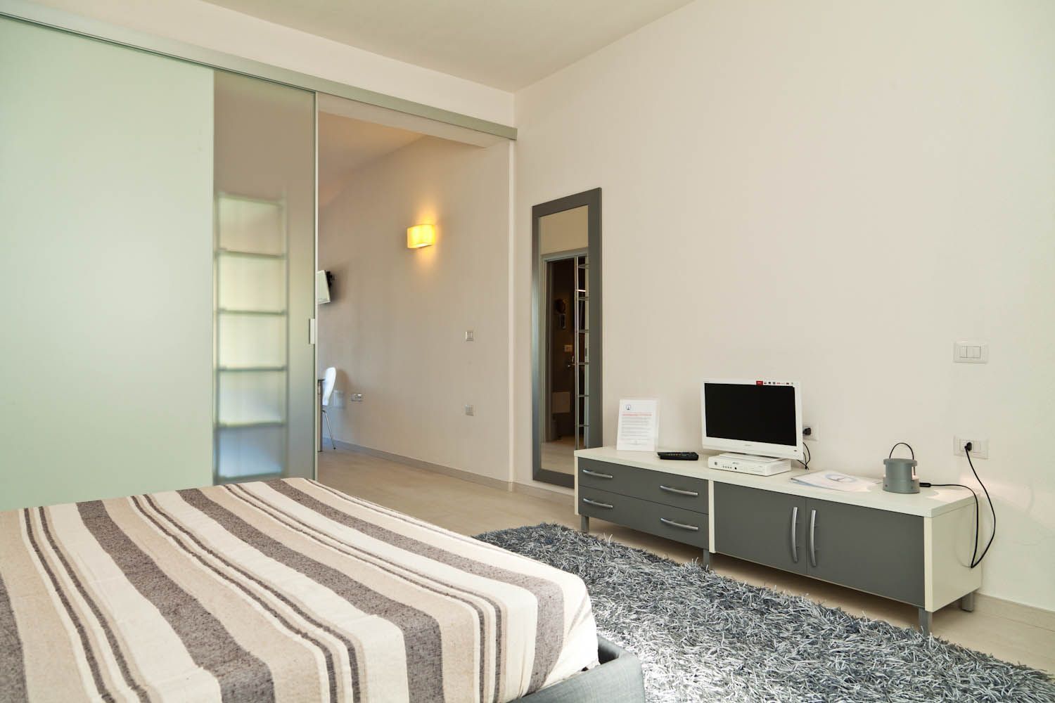 Une chambre moderne avec un lit, une télévision et un bureau doté de tiroirs.