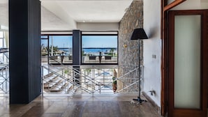 Amplio espacio interior con vista al mar, una escalera y una lámpara moderna.