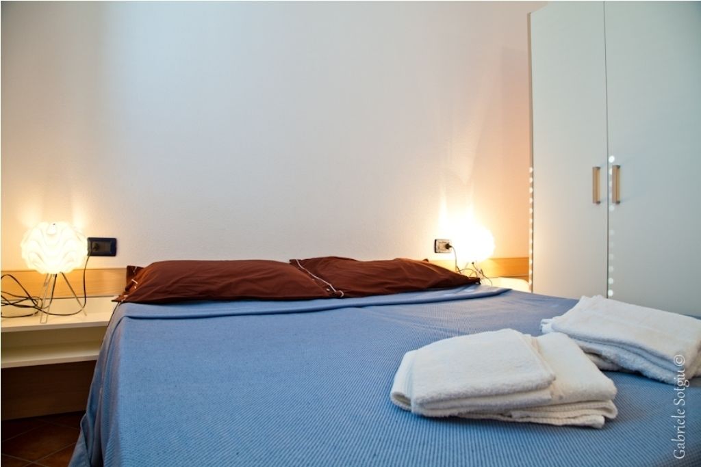 Une chambre d’hôtel comprenant un lit, deux lampes de chevet, une armoire et un ensemble de serviettes.