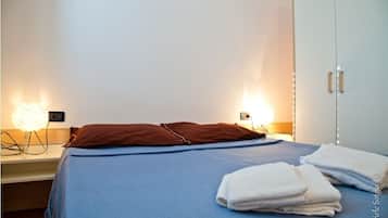 Une chambre d’hôtel comprenant un lit, deux lampes de chevet, une armoire et un ensemble de serviettes.