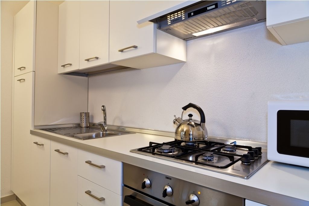 A modern kitchen with white cabinets, stainless steel appliances, and a kettle on the stove.
