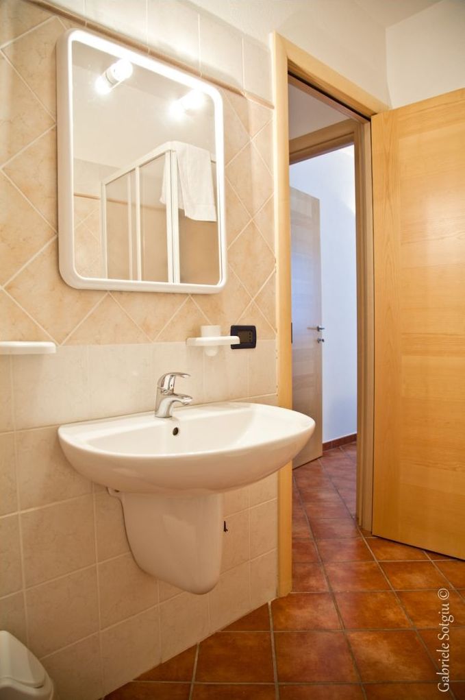 Ein Badezimmer mit einem weißen Waschbecken, einem Spiegel und einem Handtuch an der Wand.