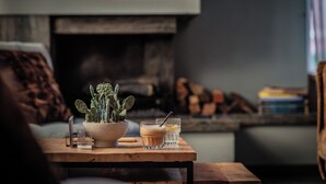 A wooden table with a cactus plant, two glasses of a beverage, and a smartphone. - Paviljoen Hotel (Rhenen)