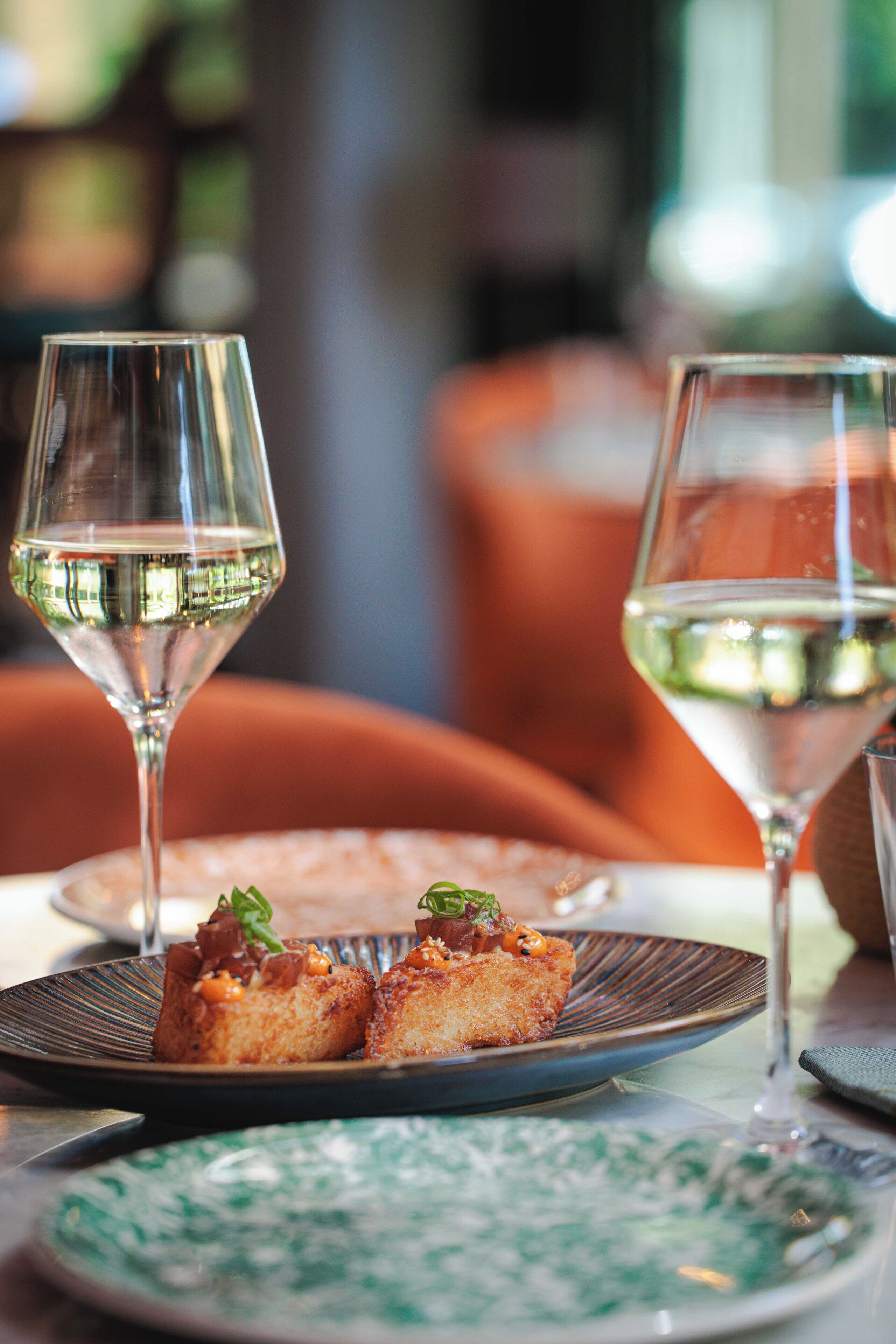 A dining table with plates of food and glasses of wine.
