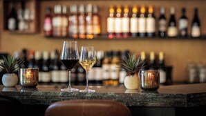 A bar counter with two glasses of wine, a candle, and small potted plants. - Paviljoen Hotel (Rhenen)