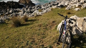 A rugged coastal landscape with rocky terrain and a mountain in the background. - Hotel Pugide (Llanes)