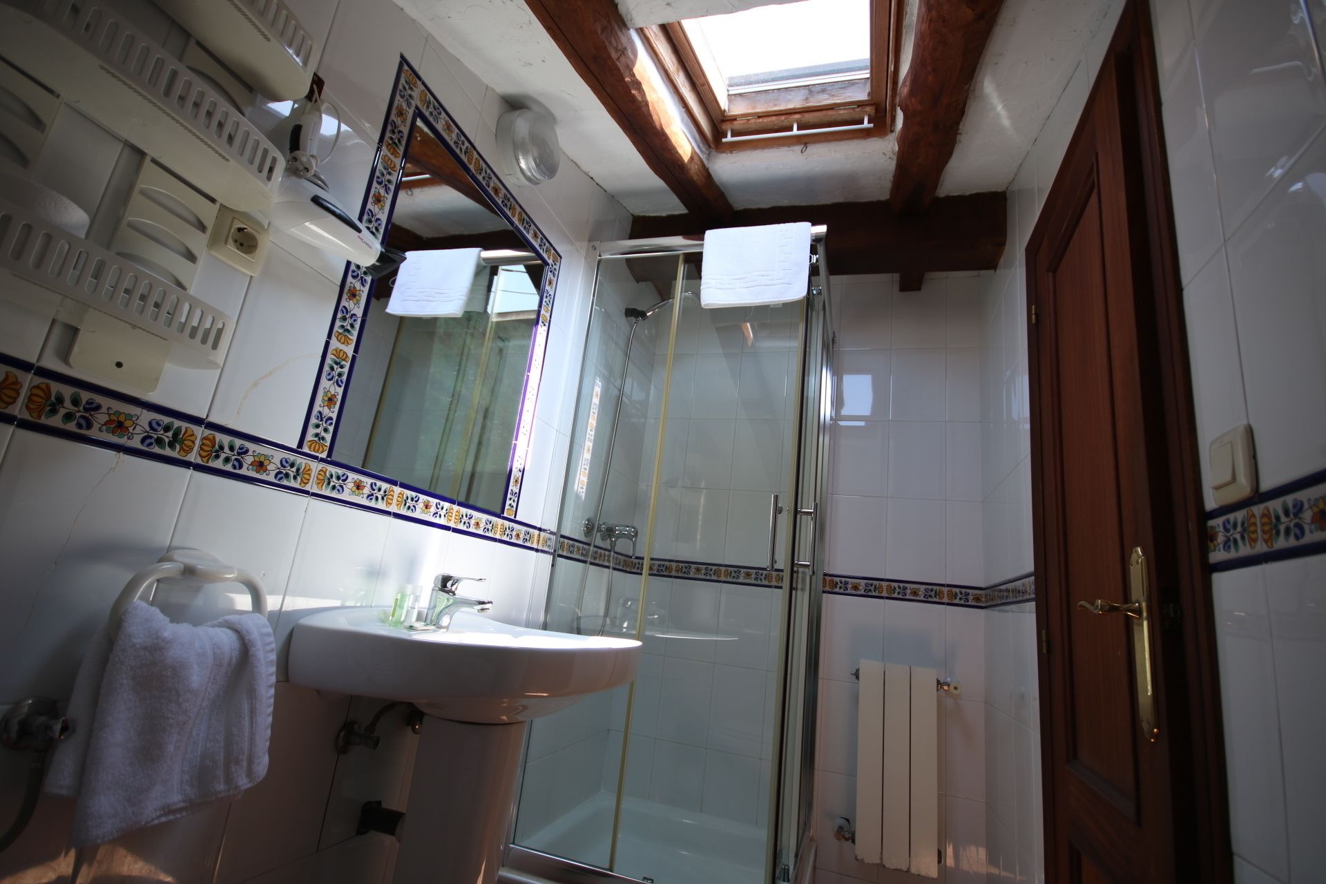 A bathroom with a sink, mirror, and shower.
