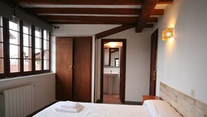 A bedroom with a bed, a window, a door, and a bathroom visible through an open door. - La Regalina (Valdes)
