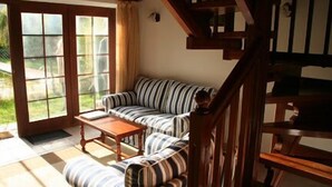 A living room with a striped sofa, a wooden coffee table, and a staircase. - La Regalina (Valdes)