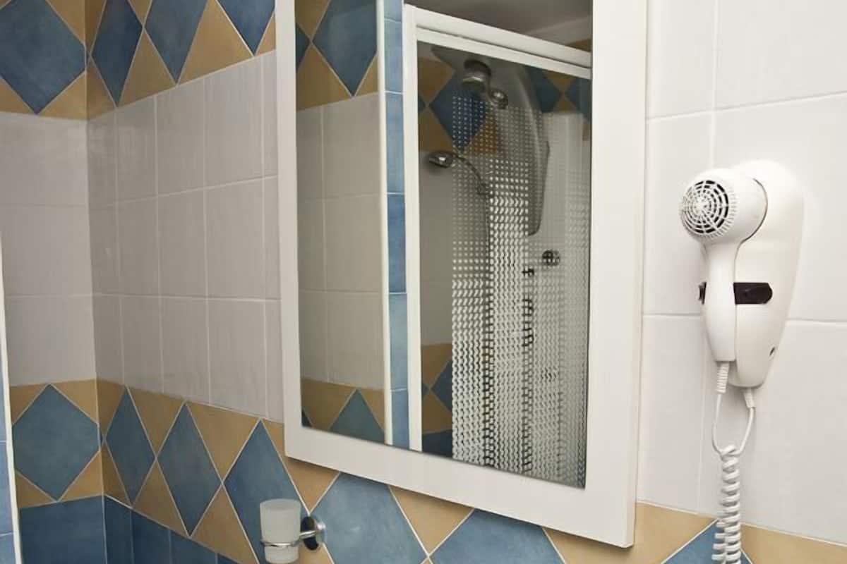 A bathroom with a white sink, a mirror, and a hairdryer mounted on the wall.