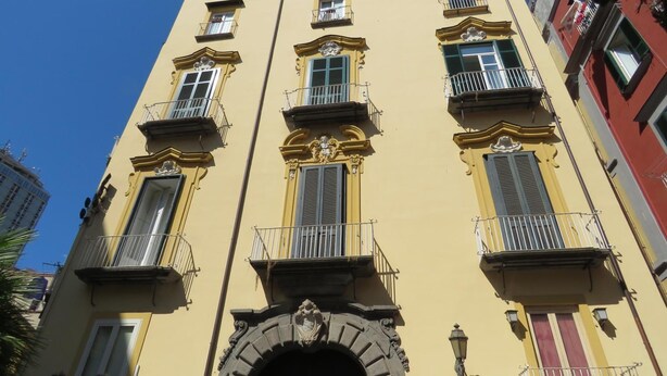 A yellow building with ornate balconies and a central archway. - Olimpo degli Dei (Naples)