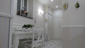 A narrow hallway with a white door, a small table with chairs, and a potted plant. - Olimpo degli Dei (Naples)