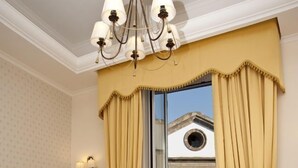 A bedroom with a bed, a chandelier, curtains, and a view of a building outside. - Olimpo degli Dei (Naples)