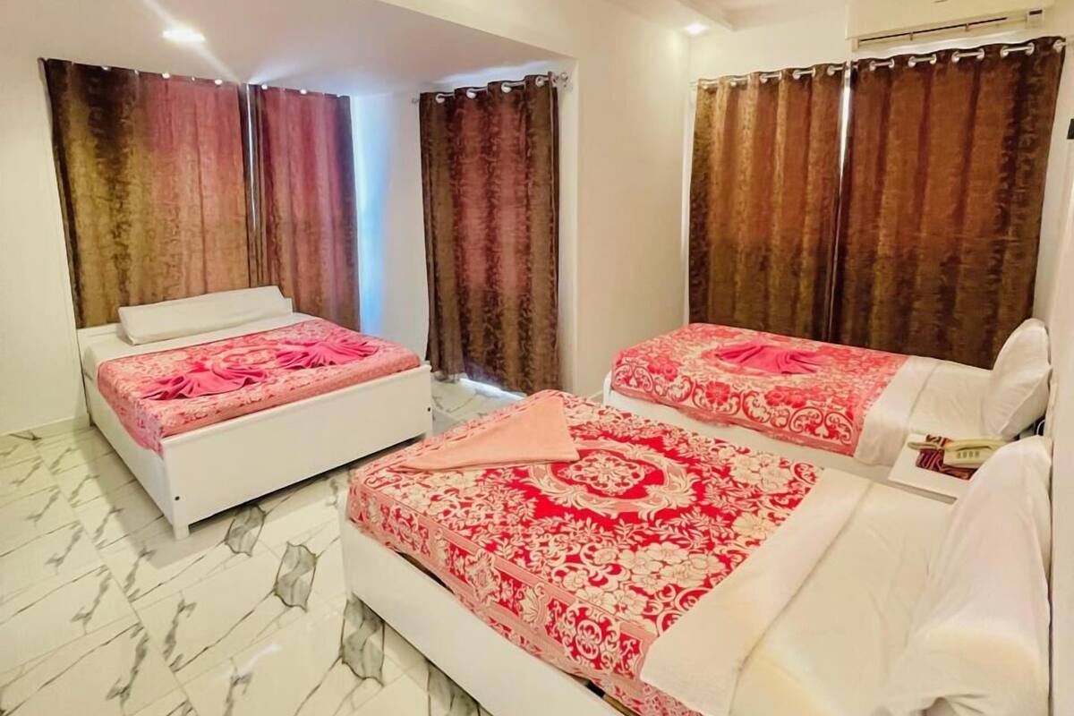 A hotel room with two beds, marble flooring, and curtains.