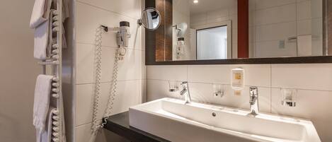 Un baño moderno con un lavabo blanco, un espejo y un perchero para toallas.