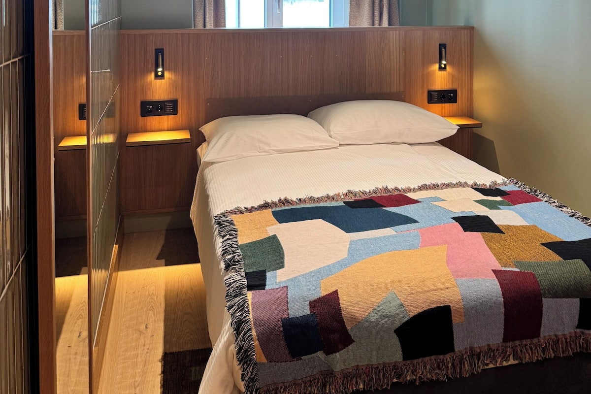 A bedroom with a bed, nightstands, a wooden wardrobe, and a window with curtains.