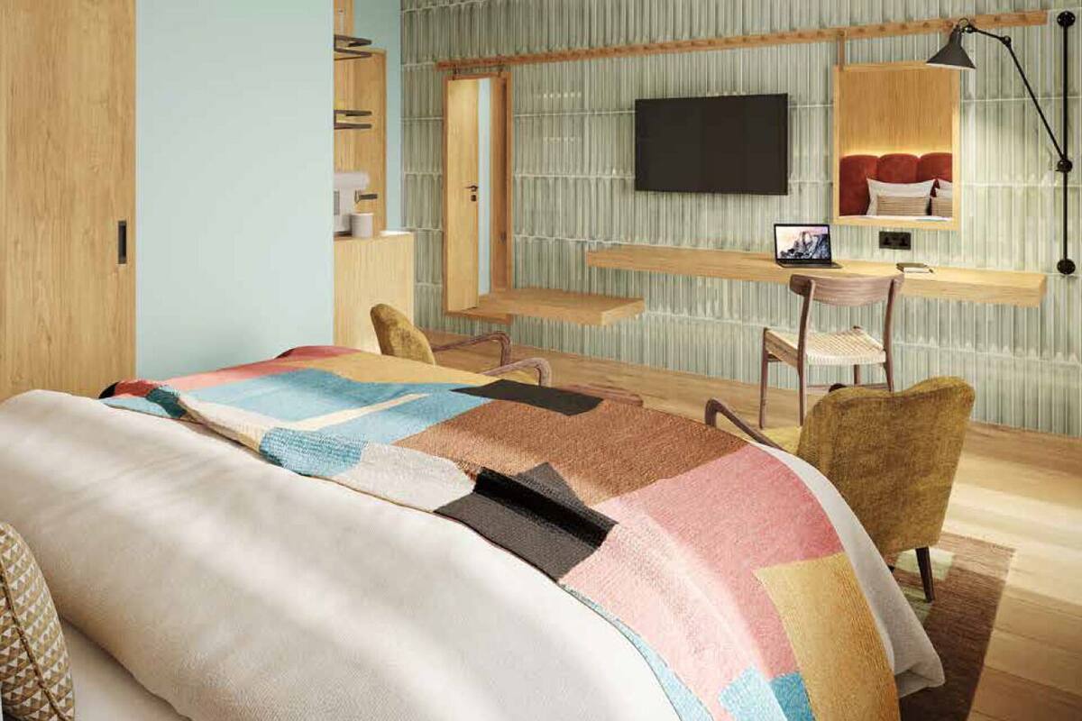 A modern bedroom with a bed, desk, chair, TV, and a mirror.