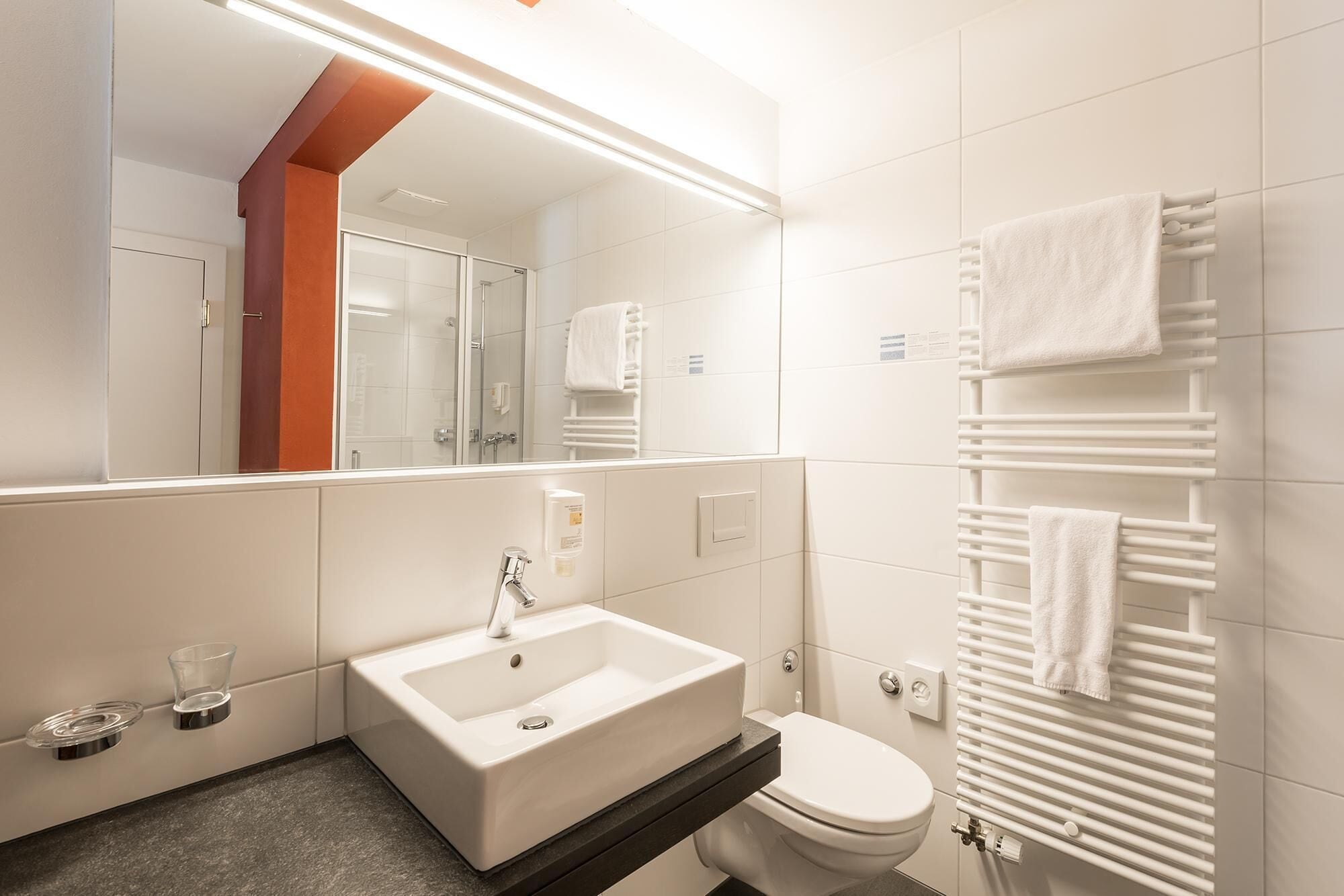 Un baño moderno con lavamanos blanco, inodoro y cabina de ducha de vidrio.