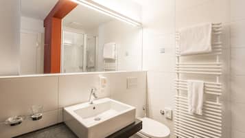 Un baño moderno con lavamanos blanco, inodoro y cabina de ducha de vidrio.