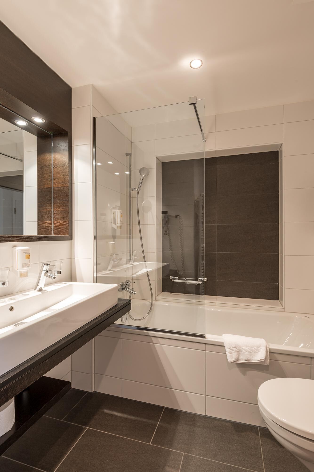 A modern bathroom with a glass-enclosed shower, a standalone bathtub, and a white toilet.