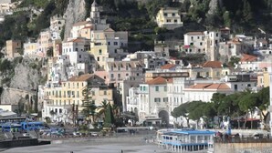 A coastal town with buildings built on a hillside, a beach in the foreground, and a rocky cliff in the background. - Hotel Croce di Amalfi (Amalfi)