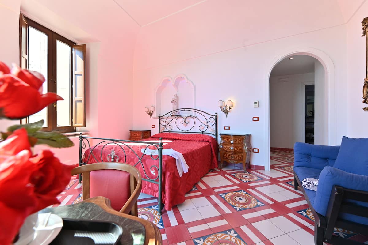 Ein Schlafzimmer mit Bett, Schlafsofa, Sessel und Kommode.