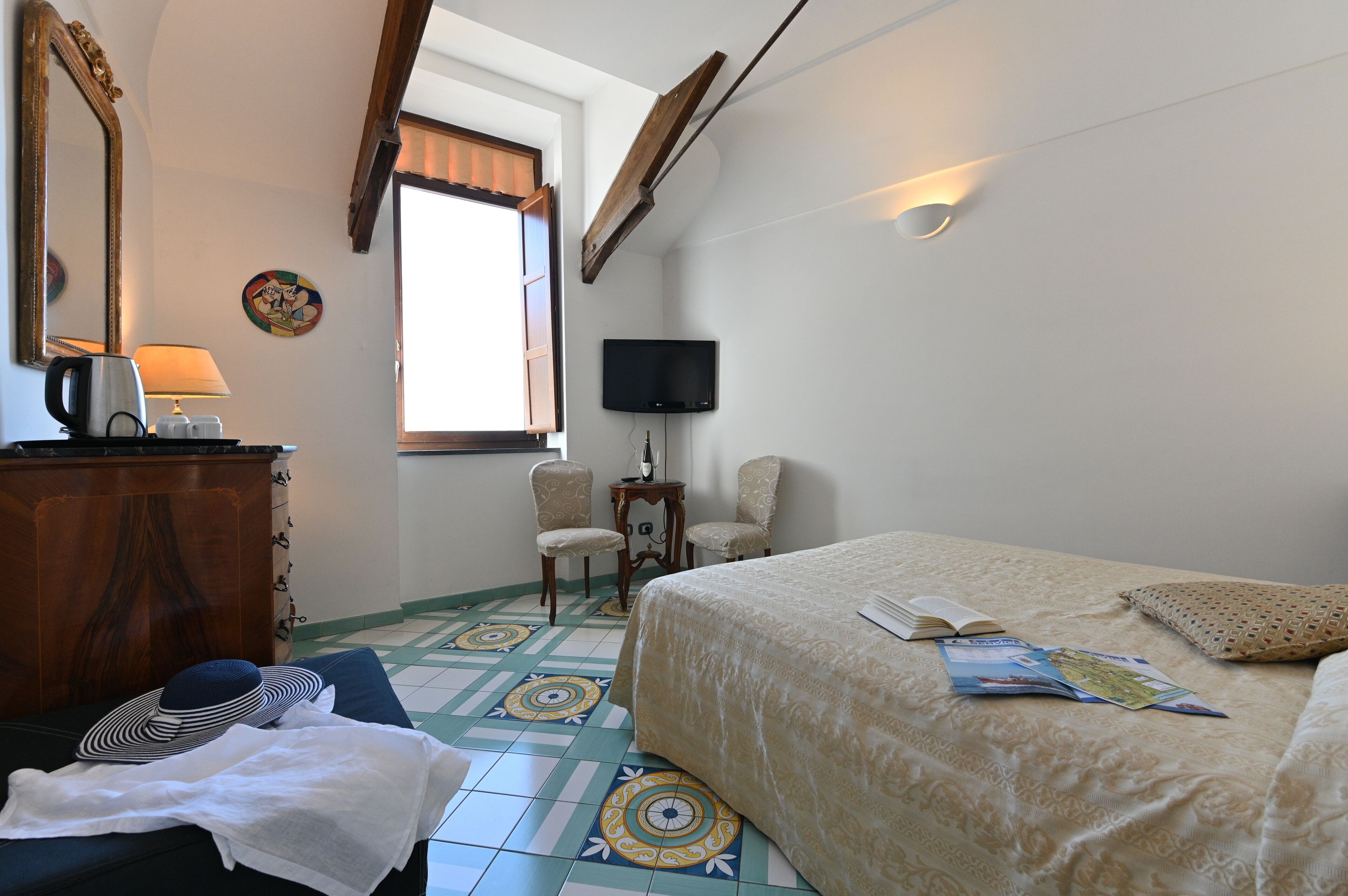 A bedroom with a bed, a desk, a chair, a television, and a window with curtains.